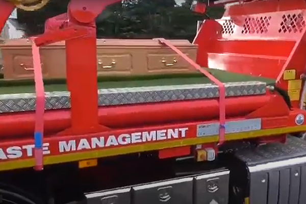A sideview of flatbed lorry carrying a coffin | Dignity Funerals