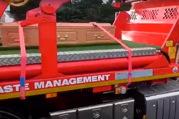 A sideview of flatbed lorry carrying a coffin | Dignity Funerals